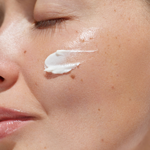 Close-up of a woman applying white cream to her face
